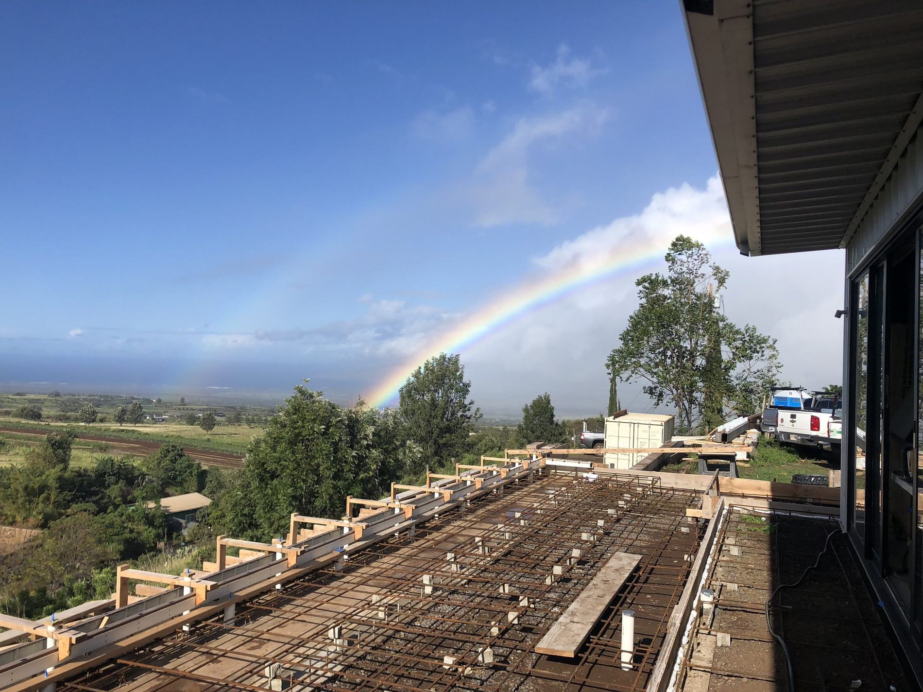 Concrete deck formed and tied on a Maui build, rainbow over the valley behind it
